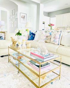 a living room filled with white furniture and lots of books on top of a coffee table