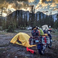 two motorcycles parked next to a tent in the woods