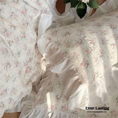 an unmade bed with white and pink flowers on it