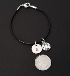 "Personalized Waxed Cord Bracelet! A Basketball charm on a black waxed cord makes the perfect gift for you or your best friend. The basketball charm is made from zinc alloy and measures 13 mm by 10 mm. The charm is not reversible. The basketball bracelet is a waxed braided rope and measures 7.25\" with a 1-2\" extender (see last picture). The lobster clasp is zinc alloy. The black cord bracelet can be personalized with a .5\" silver plated disc stamped with the initial of your choice. Each perso Black Leather Bracelet With Adjustable Cord As Gift, Nickel-free Black Charm Bracelet For Gift, Nickel-free Black Charm Bracelet As Gift, Adjustable Nickel-free Black Charm Bracelet, Black Waxed Cord Jewelry For Friendship, Adjustable Casual Charm Bracelet For Birthday, Casual Adjustable Charm Bracelet For Birthday, Adjustable Nickel-free Black Leather Bracelet, Adjustable Black Nickel-free Leather Bracelet