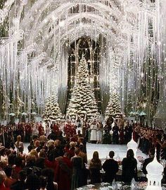 a large group of people standing in front of a christmas tree with lots of lights