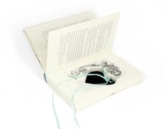 an open book with a mouse in it on top of a white table next to a string