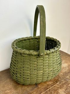 a green basket sitting on top of a wooden table