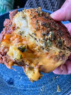 a hand holding a piece of food on top of a blue plate