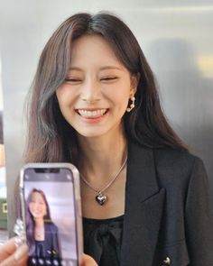 a woman holding up a cell phone to take a selfie with her face on the screen