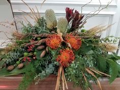 an arrangement of flowers and greenery on a table