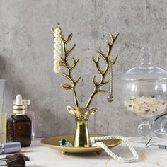 a gold deer head on a plate with pearls and beads hanging from it's antlers