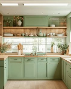 a kitchen filled with lots of green cupboards and counter top space next to a window