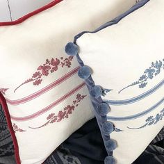 two decorative pillows with pom poms on them sitting next to eachother