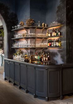 a bar with shelves filled with bottles and glasses next to a wall mounted wine rack