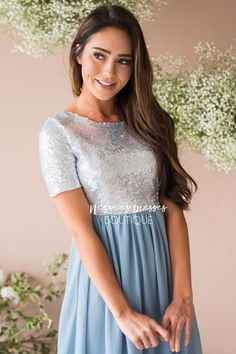 a woman wearing a blue dress with sequins on the top and sleeves, smiling