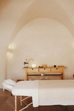 a room with a bed, table and two chairs in front of an arched wall