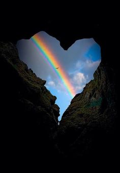 a heart shaped hole with a rainbow in the background