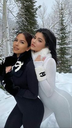 two beautiful women standing next to each other in the snow