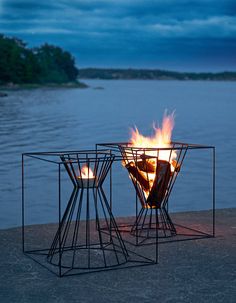 two fire pits sitting next to each other near the water