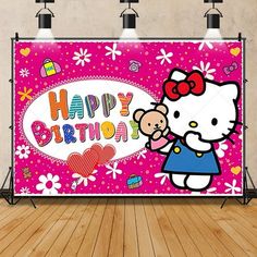 a pink hello kitty birthday backdrop on a wooden floor with spotlights in the background