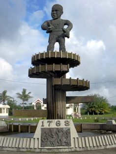 a statue of a man standing on top of a wooden structure in the middle of a park