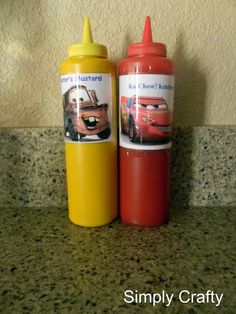 two children's cups with cars on them sitting next to each other in front of a wall