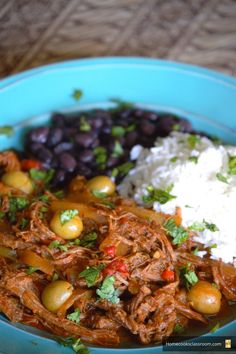 a blue bowl filled with meat, beans and rice