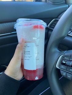 a person holding a cup in their hand while sitting in the driver's seat