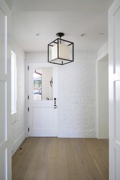 an empty room with white brick walls and wood flooring is seen through the open door