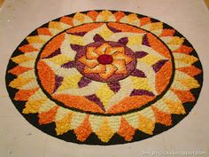 an orange and yellow rug on the floor in front of a white table top with a flower design