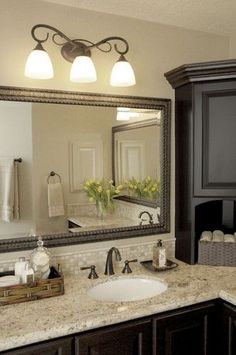 a bathroom with a large mirror above the sink and lights on either side of it