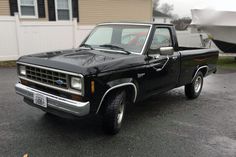 a black pickup truck parked in front of a boat