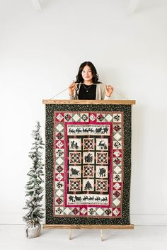 a woman is holding up a quilt