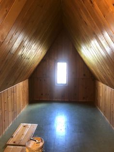 an empty attic with wooden walls and flooring