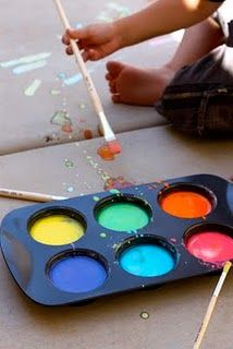 the child is painting on the floor with paintbrushes and watercolors in it