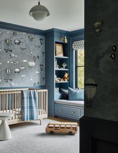 a baby's room decorated in blue and grey with wallpapers on the walls