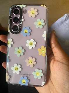 someone is holding their phone case with smiley face flowers on the front and bottom cover