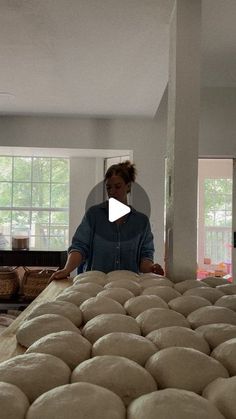 a woman standing in front of stacks of doughnuts on top of a table