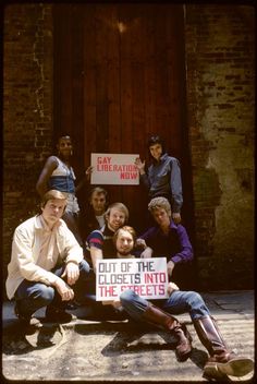 a group of people sitting on the ground holding signs that read out of the closet into the streets