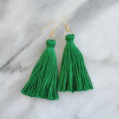 green tasselled earrings on marble surface