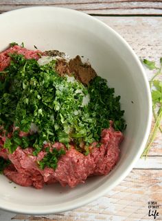 a white bowl filled with meat and herbs