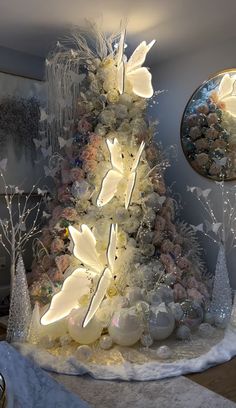 a lighted christmas tree in the corner of a room with flowers and butterflies on it