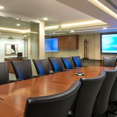 an empty conference room with chairs and a projector screen in the back drop off wall