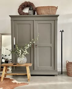 a vase with flowers sitting on top of a wooden table next to a gray cabinet