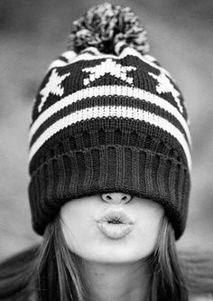 black and white photograph of a woman wearing a knitted hat with pom - pom