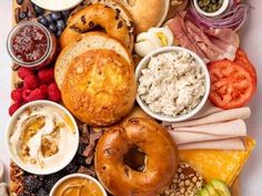 an assortment of different types of food on a platter, including bagels and fruit