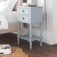 a white night stand with two drawers and a magazine on the floor next to it