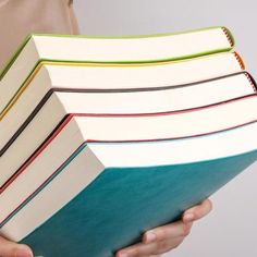 a person holding a stack of books in their hands