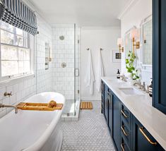 a bathroom with blue cabinets and a white bathtub next to a walk in shower