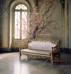 a white couch sitting in front of a window next to a tree with pink flowers