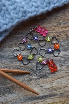 a group of heart shaped charms sitting on top of a wooden table next to pencils