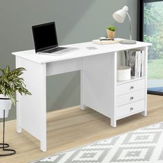 a computer desk with a laptop on top of it next to a potted plant