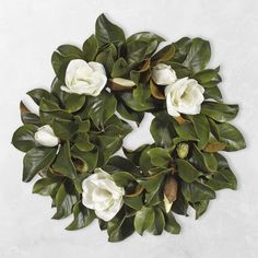 white flowers and green leaves are arranged in a circle on a white background with space for text