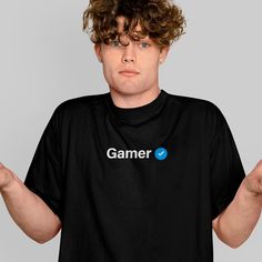 Level up your wardrobe with our Gamer Verified Unisex T-Shirt. Crafted from premium, soft cotton, this short sleeve tee offers both comfort and durability, making it perfect for long gaming sessions or casual outings. The unisex design ensures a great fit for both men and women, allowing you to proudly display your gamer status. Features: - Premium Material: Made from 100% soft and breathable cotton for all-day comfort. - Unisex Design: Perfectly fits both men and women, offering versatile style Gamer Style Cotton T-shirt With Logo Print, Black Short Sleeve Gamer Tops, Gamer Cotton T-shirt Pre-shrunk, Gamer Style Cotton T-shirt With Letter Print, Gamer Style Short Sleeve Top With Letter Print, Pre-shrunk Cotton Gamer T-shirt, Gamer Crew Neck Top With Letter Print, Gamer Style Crew Neck Top With Logo Print, Gamer Tops With Letter Print And Crew Neck